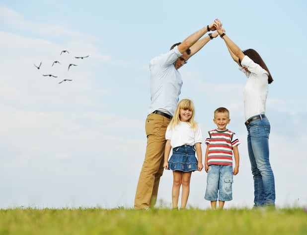 Young family on green summer grass meadow building dream new home